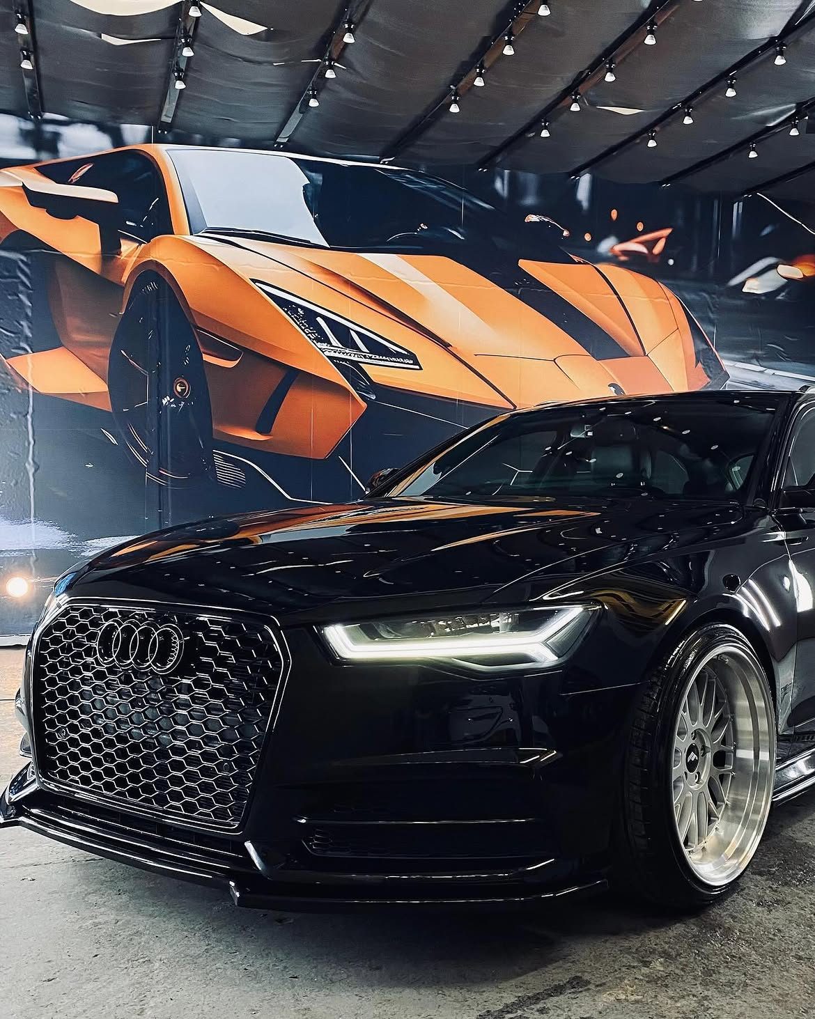 Black Audi in front of a supercar mural